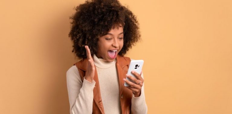 A woman holding a cell phone and smiling.