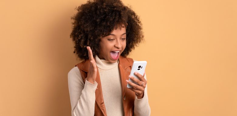 A woman holding a cell phone and smiling.