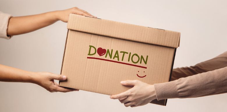 Two people holding a cardboard box that says "donation" on it.