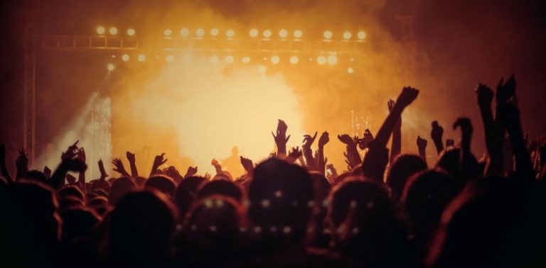 The crowd at a concert, with yellow and orange lighting.