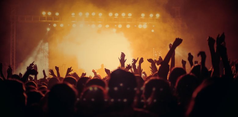 The crowd at a concert, with yellow and orange lighting.