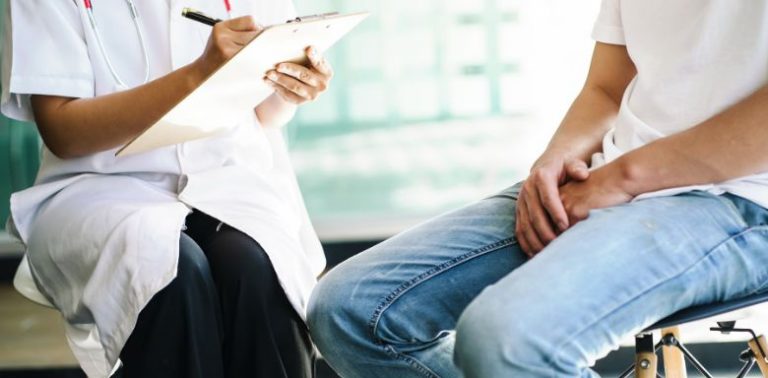 A male patient sitting down and talking to a doctor.